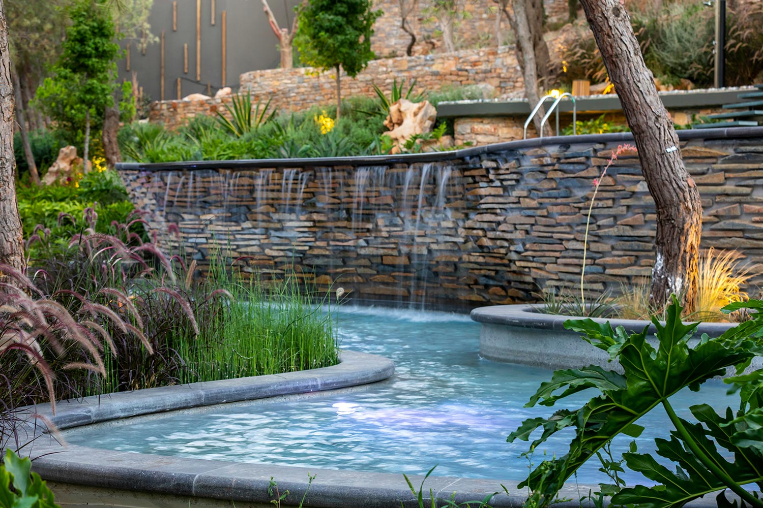 Peaceful garden with waterfall wall and lush landscaping around a pond