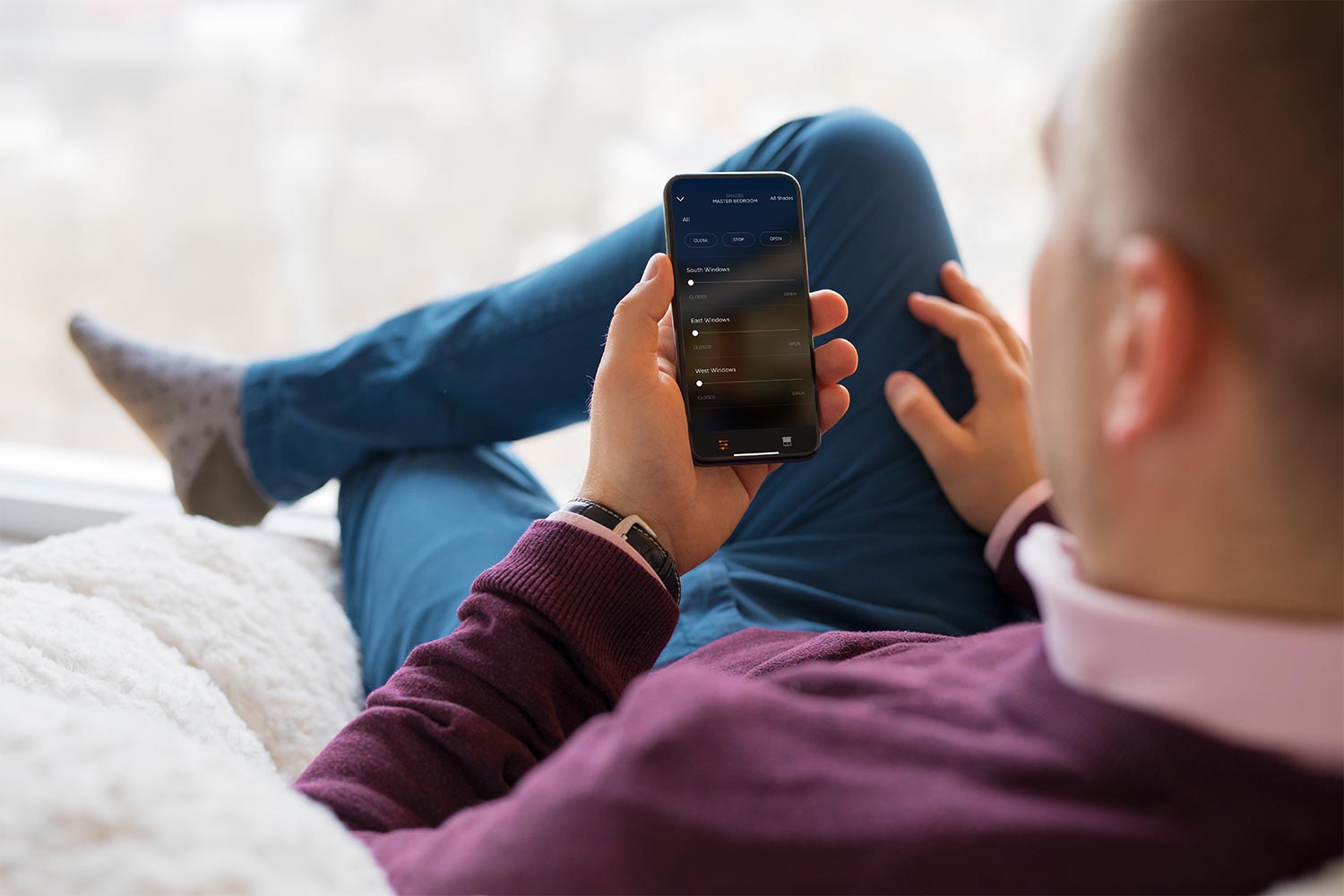 Man using a smartphone app to control smart home window settings