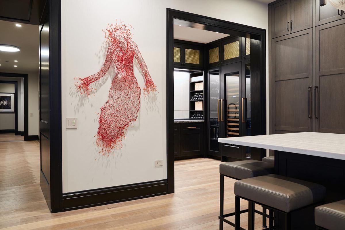 Artistic red wire sculpture of a woman mounted on interior wall