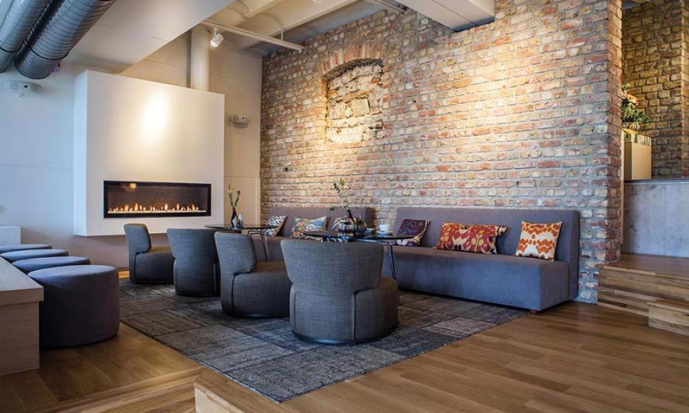 Cozy lounge with exposed brick wall, modern fireplace, and stylish seating.
