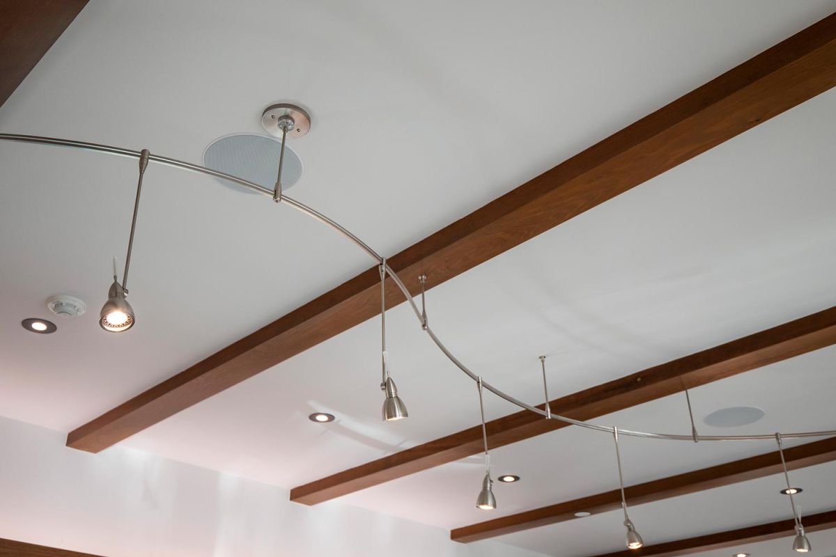 Track lighting system mounted on white ceiling with wooden beams