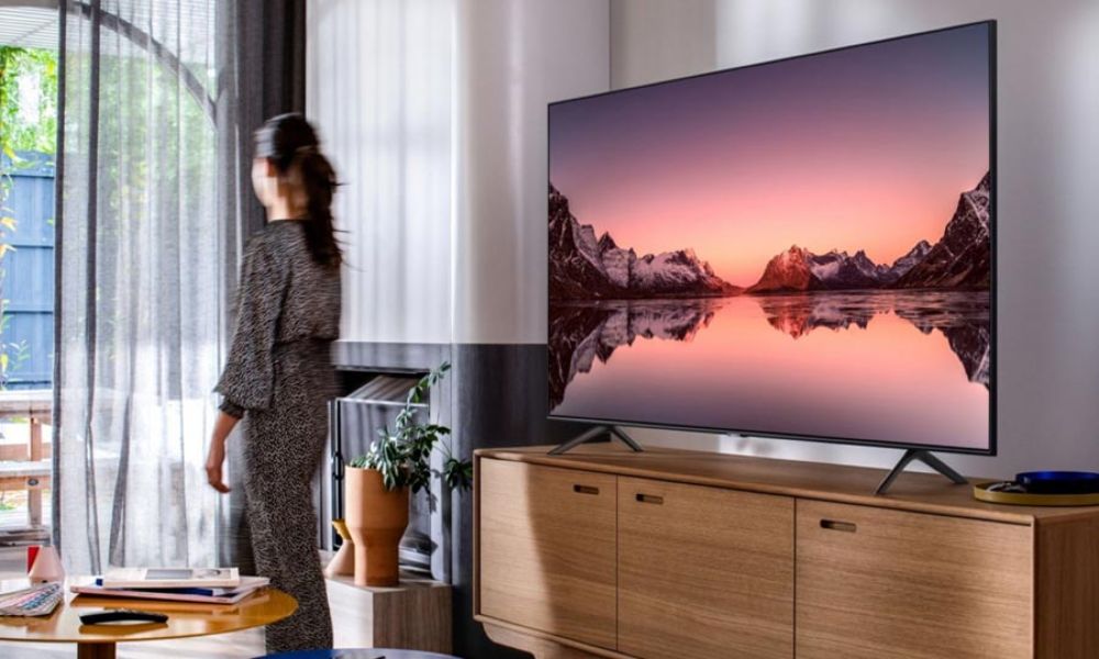 Large TV displaying a scenic sunset, placed on a stylish wooden console.
