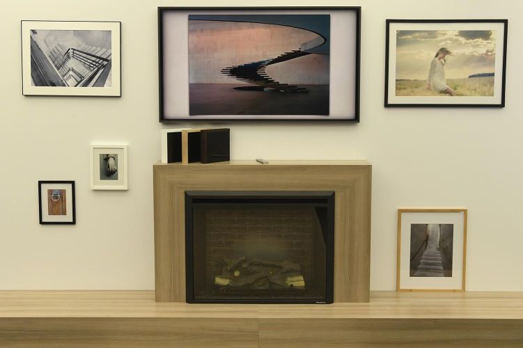 A modern living space with a Samsung Frame TV above a fireplace, framed by artistic wall decor.