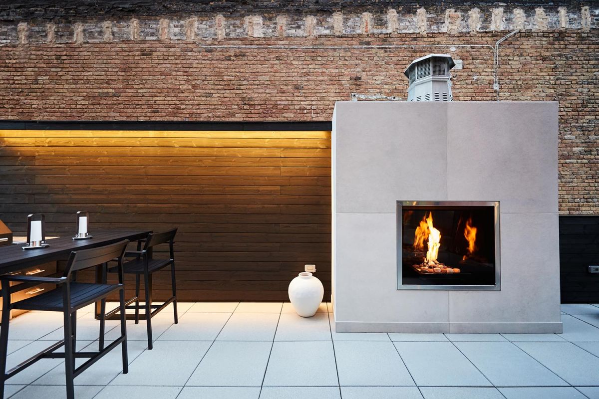 Outdoor patio with modern fireplace, tall chairs, and brick backdrop