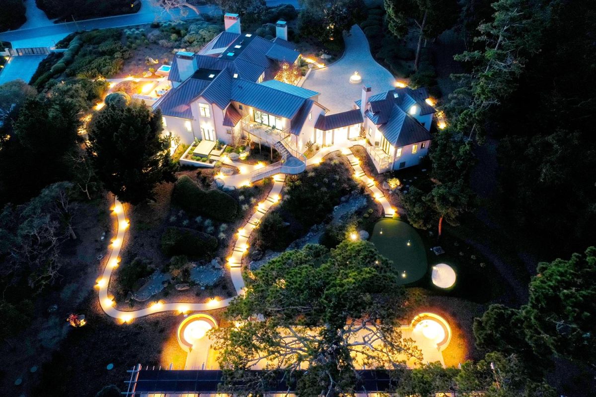Rear night view of a house with glowing garden paths and patio lighting
