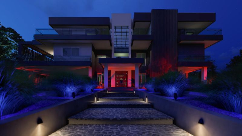 Luxury home exterior at night with dramatic landscape lighting.