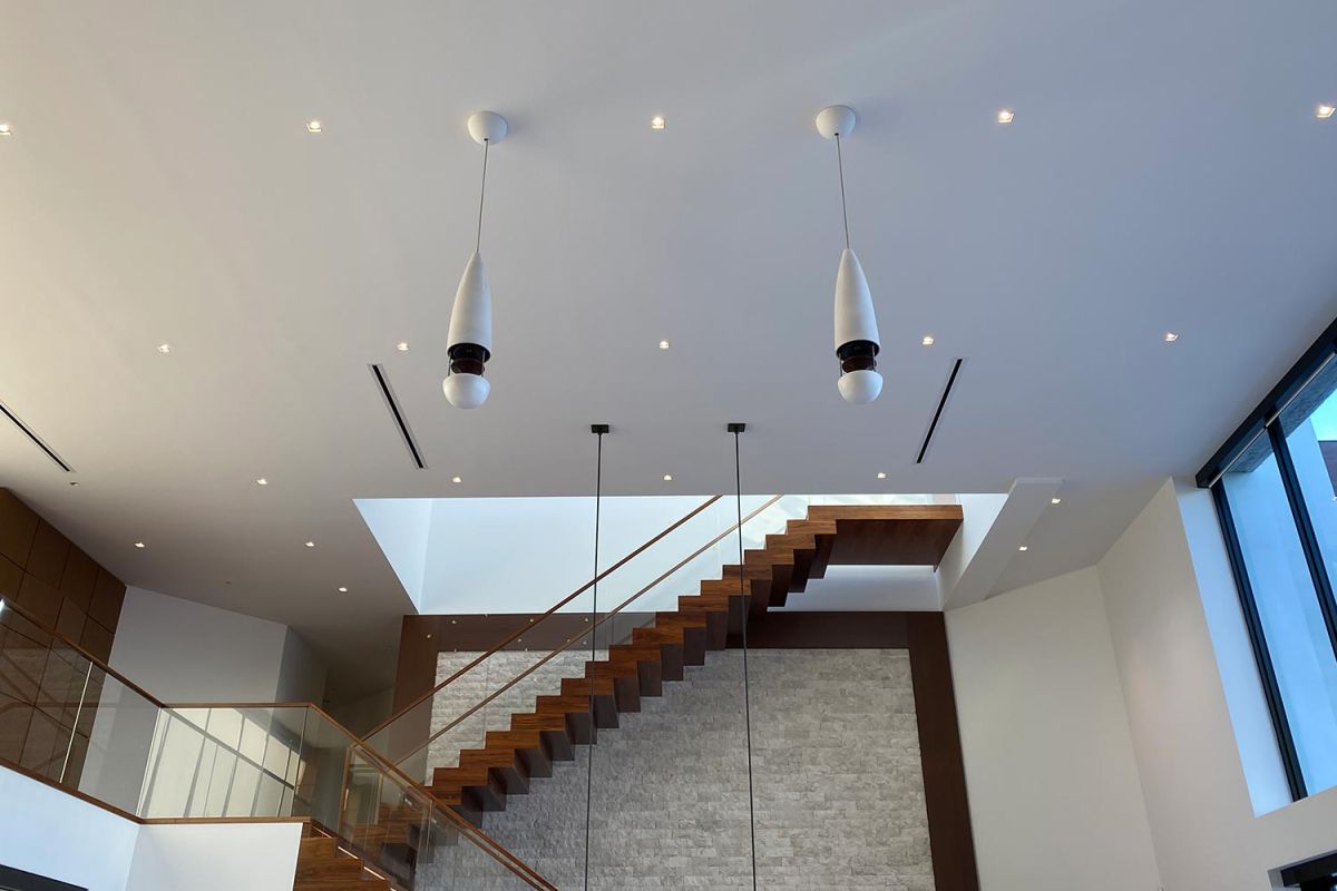 View of floating staircase under high ceiling with modern lighting